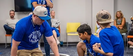 An instructor works with children during the coding summer camp.